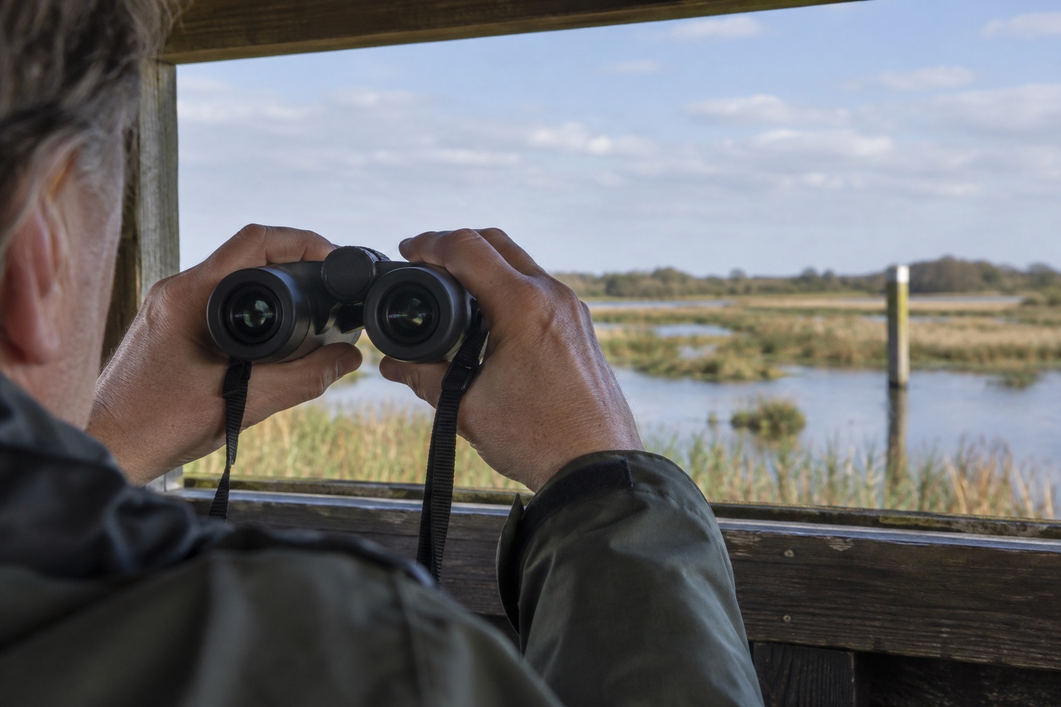 Observer checking binocular alignment against a distant post from a hide