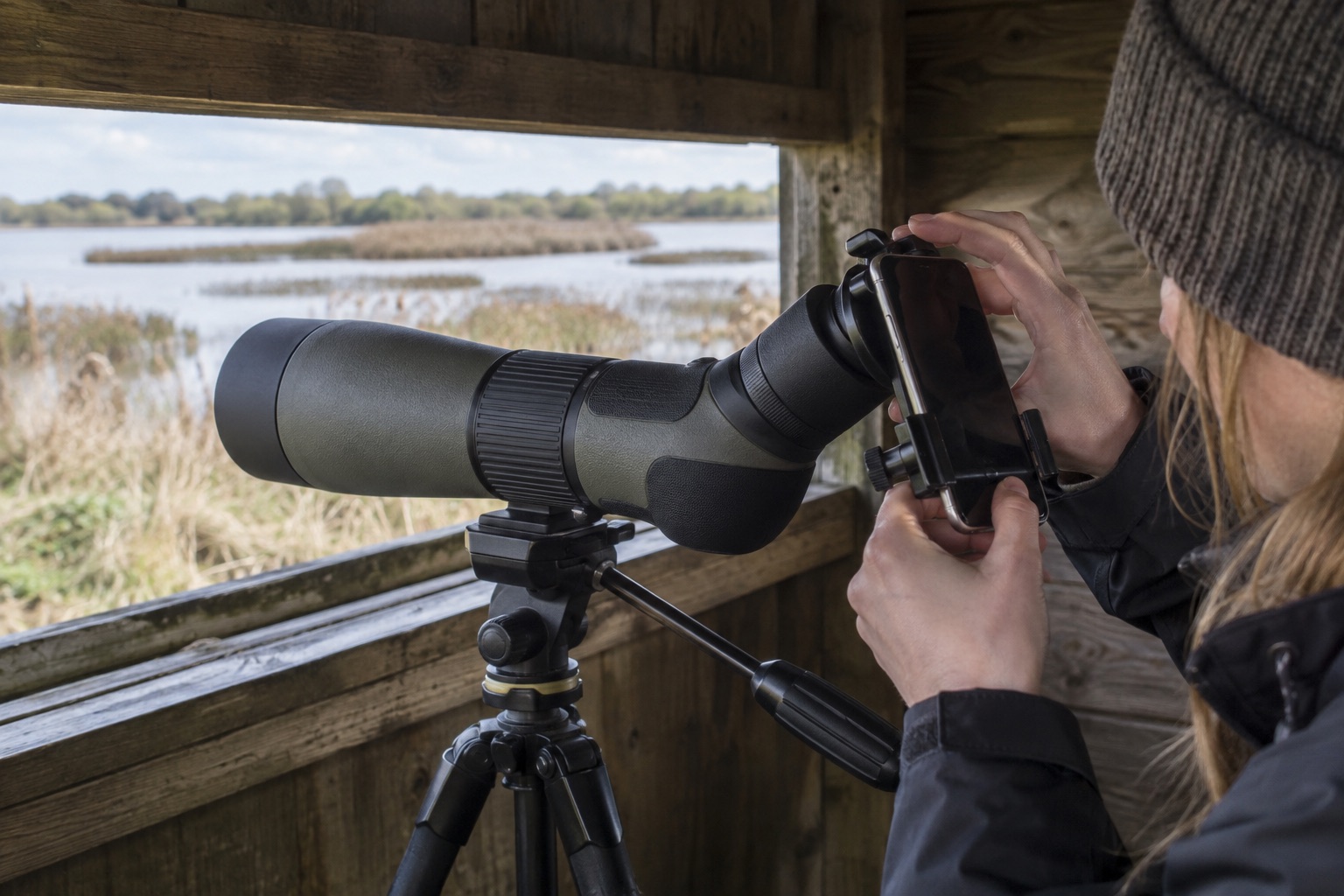 Smartphone mounted behind a spotting scope eyepiece using a black adapter